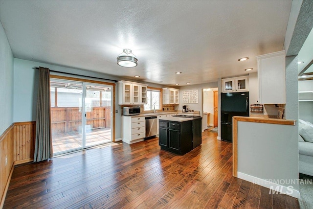 kitchen featuring dark wood finished floors, a wainscoted wall, stainless steel appliances, a kitchen island, and white cabinetry