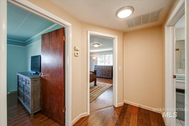 hall featuring baseboards, visible vents, and dark wood-style flooring