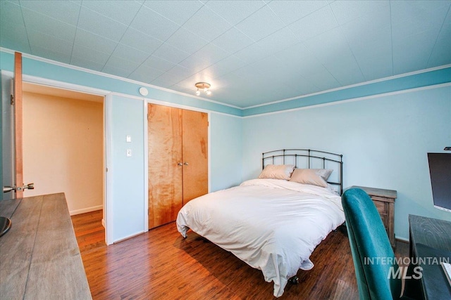 bedroom with wood finished floors and ornamental molding