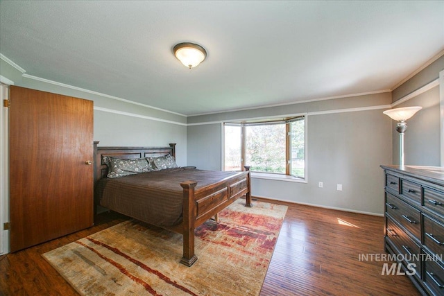 bedroom featuring baseboards, crown molding, and wood finished floors