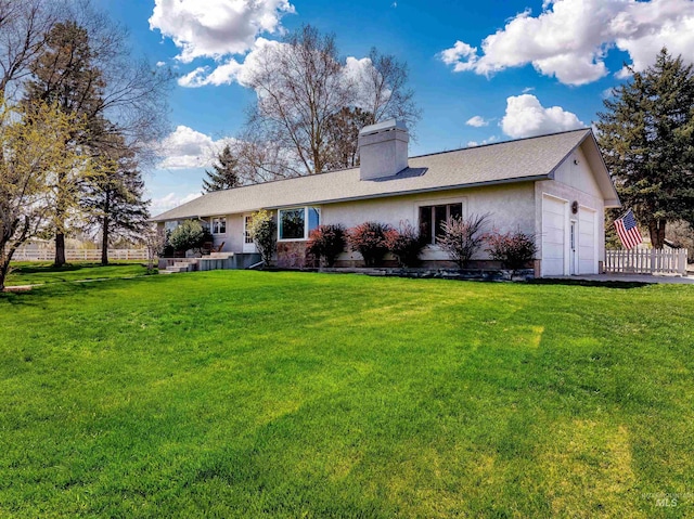back of house featuring an attached garage, a lawn, a chimney, and fence