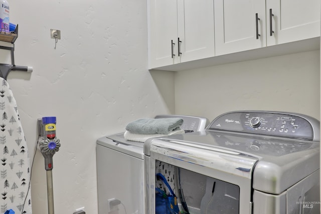 clothes washing area featuring washer and dryer and cabinets