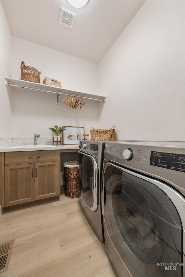 5222 S Montague Way, Meridian, ID 83642 - washroom featuring separate washer and dryer, cabinet space, and light wood-style flooring