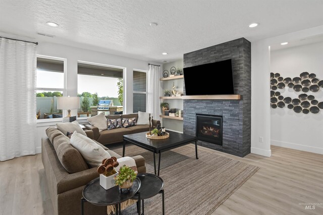5720 W Ladle Rapids St, Meridian, ID 83646 - living room featuring a stone fireplace, plenty of natural light, light wood finished floors, a textured ceiling, and recessed lighting