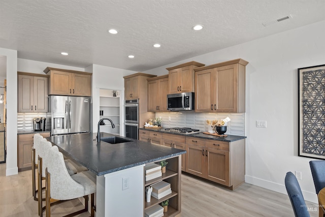 5720 W Ladle Rapids St, Meridian, ID 83646 - kitchen featuring a sink, stainless steel appliances, dark countertops, light wood-type flooring, and a textured ceiling