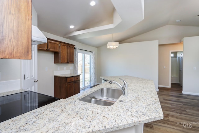 kitchen featuring a sink, vaulted ceiling, light stone countertops, dark wood-style floors, and decorative light fixtures