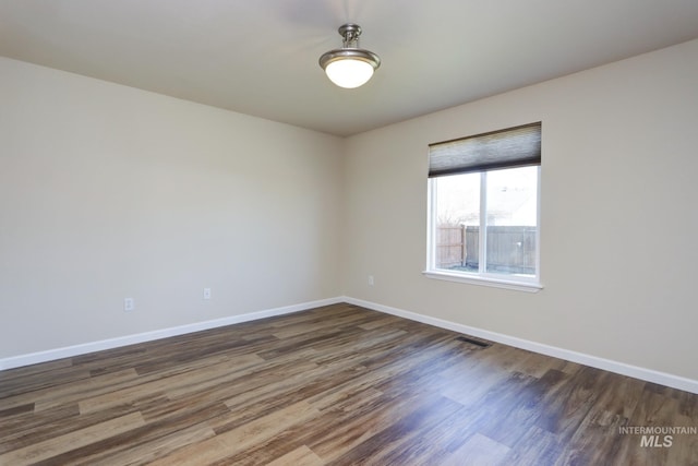 spare room featuring visible vents, baseboards, and wood finished floors