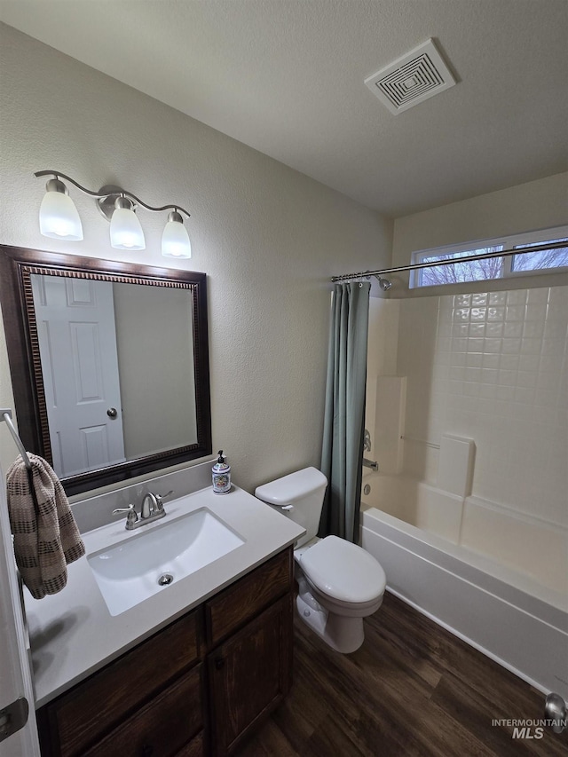 full bath with shower / tub combo with curtain, visible vents, toilet, vanity, and wood finished floors