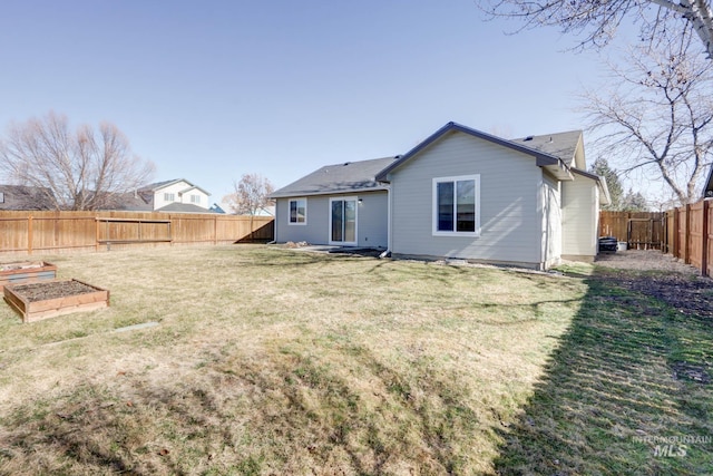 back of property featuring a garden, a lawn, and a fenced backyard