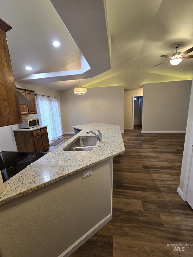 kitchen with dark wood-style flooring, a sink, baseboards, vaulted ceiling, and stainless steel microwave