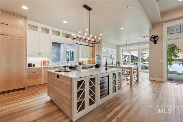 kitchen featuring recessed lighting, a kitchen island with sink, light wood-style floors, and light brown cabinets