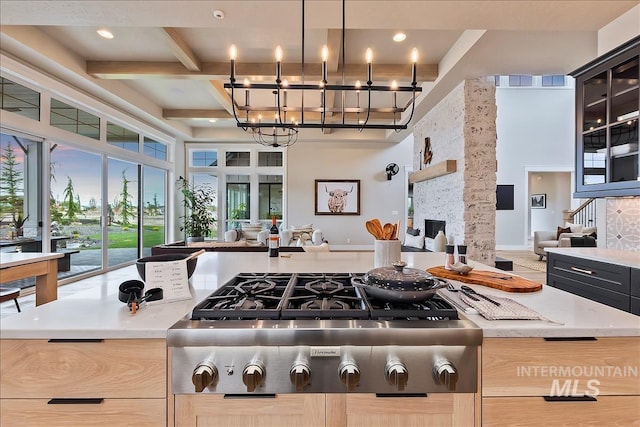 kitchen with beamed ceiling, open floor plan, stainless steel gas stovetop, and an inviting chandelier