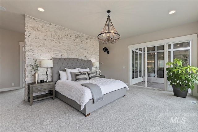 carpeted bedroom featuring baseboards, an accent wall, a notable chandelier, recessed lighting, and access to exterior