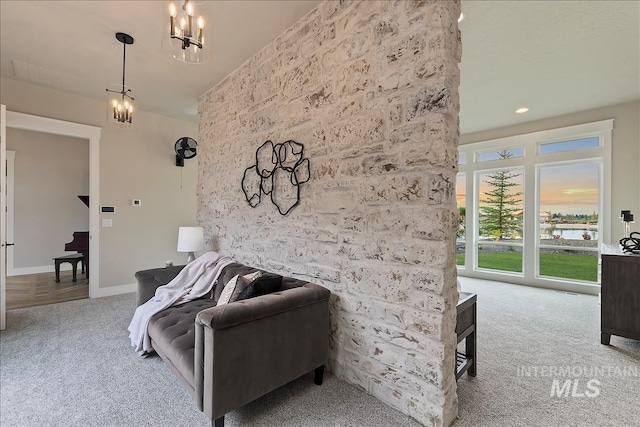 carpeted living room with a notable chandelier and baseboards