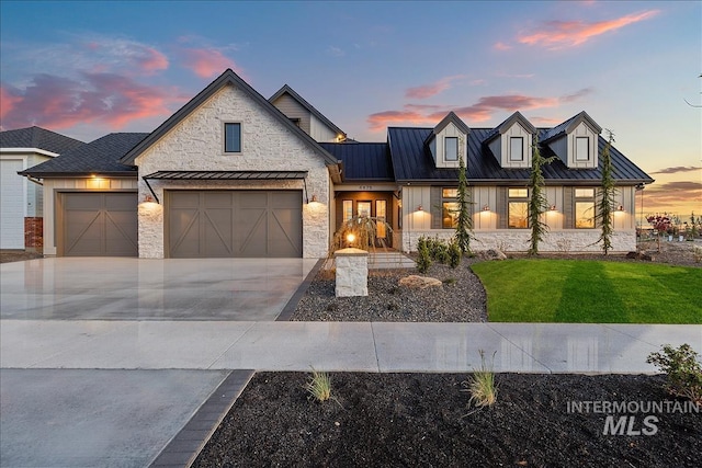 view of front of property featuring a standing seam roof, metal roof, stone siding, an attached garage, and concrete driveway