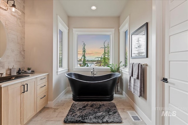 bathroom with tasteful backsplash, visible vents, baseboards, a soaking tub, and vanity