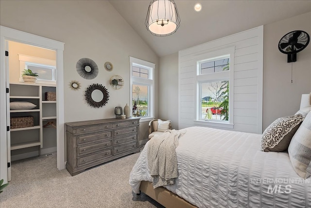 carpeted bedroom with a walk in closet and high vaulted ceiling