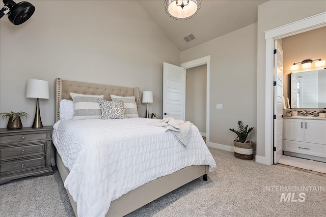 bedroom featuring baseboards, ensuite bathroom, visible vents, high vaulted ceiling, and light colored carpet