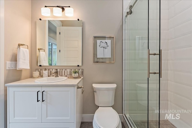 bathroom featuring toilet, vanity, and a stall shower