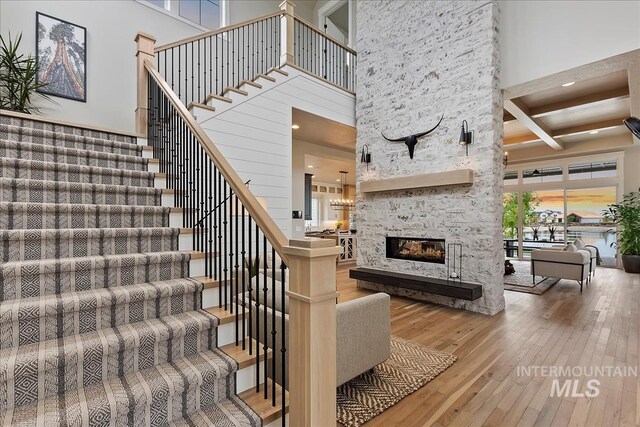 staircase with a stone fireplace, recessed lighting, hardwood / wood-style floors, and a towering ceiling