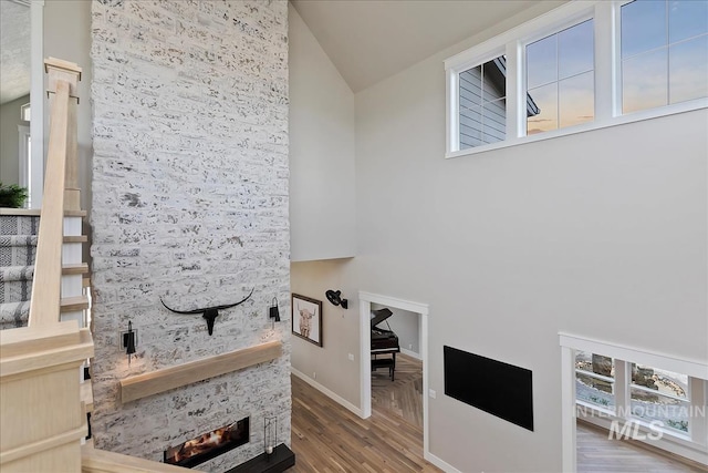 interior space with a stone fireplace, baseboards, and wood finished floors