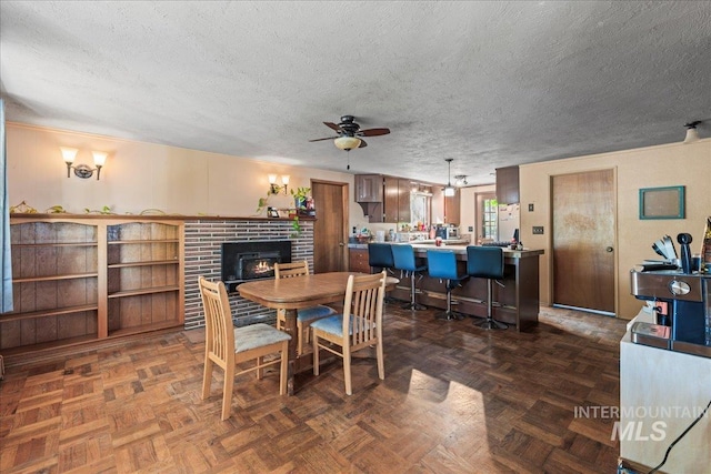 dining space with a textured ceiling, ceiling fan, and a fireplace