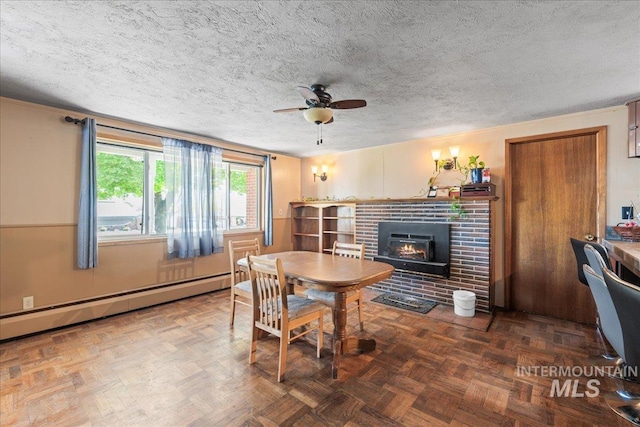 dining space with a textured ceiling, ceiling fan, a baseboard heating unit, and a fireplace