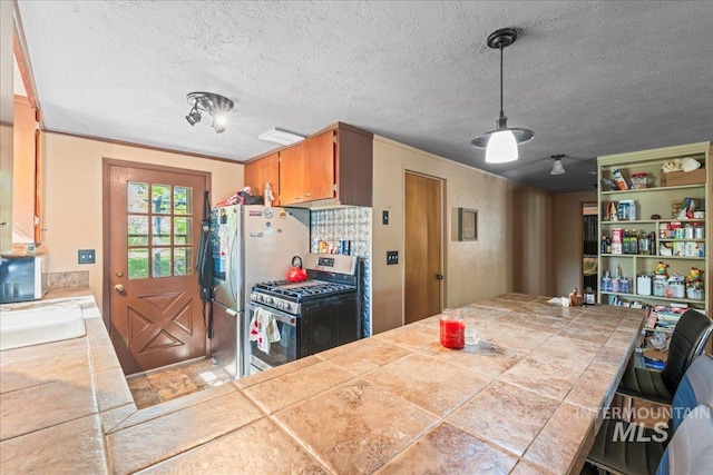 kitchen with a sink, tile counters, stainless steel appliances, and a textured ceiling