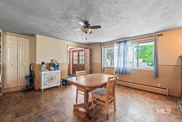 dining area featuring wainscoting, ceiling fan, a baseboard heating unit, and a textured ceiling