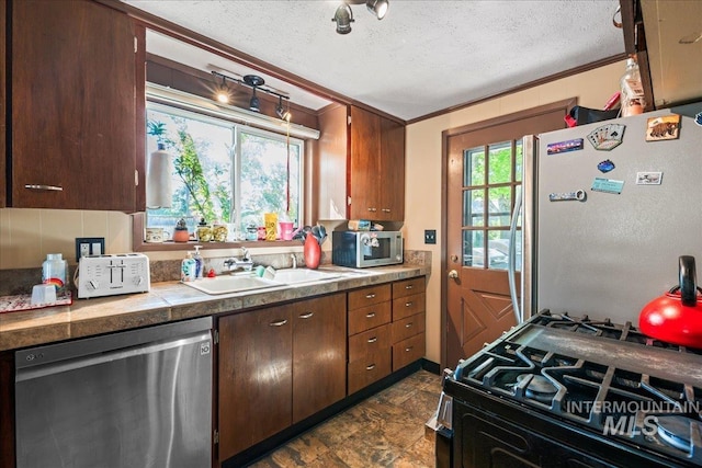 kitchen featuring crown molding, a sink, a textured ceiling, and appliances with stainless steel finishes