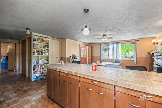 kitchen featuring light countertops, a textured ceiling, and brown cabinetry