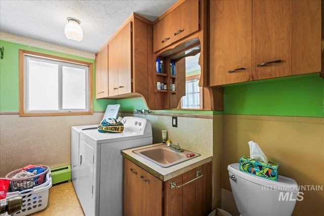 washroom with a sink, cabinet space, washing machine and dryer, and a healthy amount of sunlight