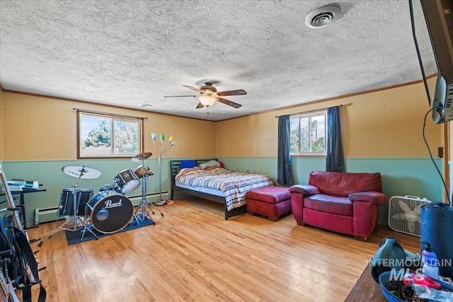 bedroom with visible vents, ornamental molding, a baseboard radiator, and wood finished floors