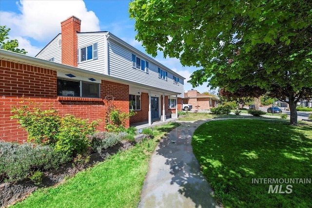 view of side of property featuring a yard, brick siding, and a chimney
