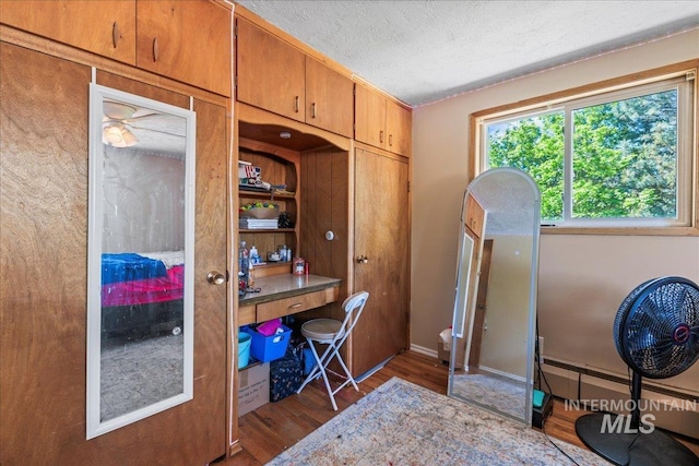 interior space featuring a textured ceiling, wood finished floors, and a baseboard radiator