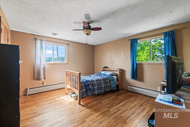 bedroom featuring a baseboard radiator, wood finished floors, and multiple windows