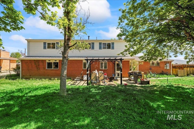 back of property with brick siding, a patio, a fenced backyard, a yard, and a pergola
