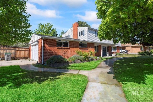 traditional-style home featuring a chimney, a front yard, a garage, brick siding, and fence