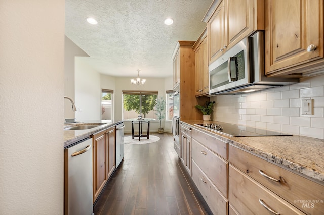 8235 W Tether St, Boise, ID 83709 - kitchen featuring stainless steel appliances, a chandelier, dark wood-style flooring, decorative backsplash, and a sink