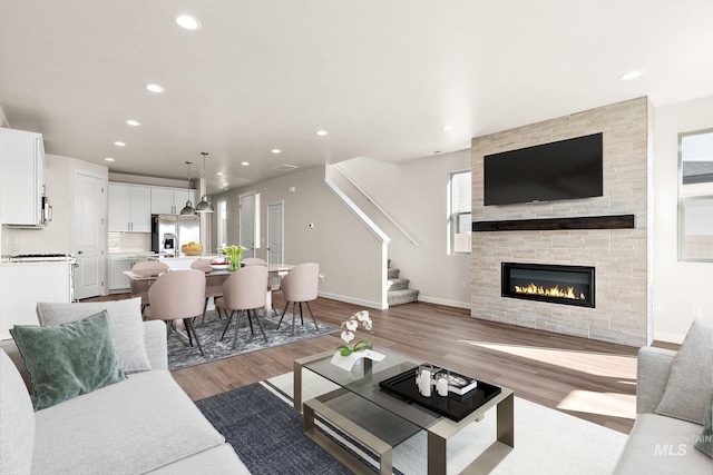 living room with recessed lighting, stairway, a fireplace, light wood finished floors, and baseboards