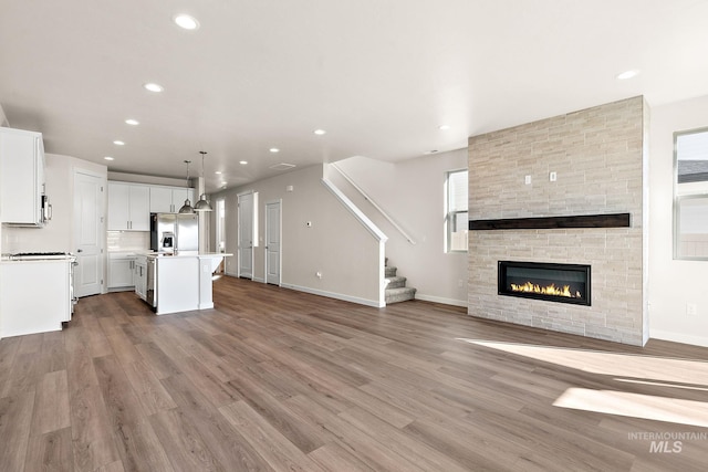 unfurnished living room with recessed lighting, light wood-type flooring, and stairs