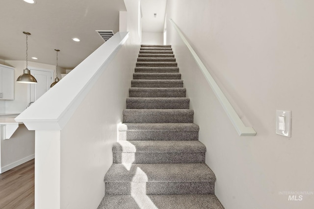 staircase with recessed lighting, wood finished floors, and visible vents