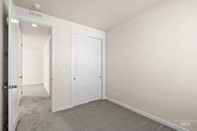 unfurnished bedroom featuring carpet, visible vents, a closet, and baseboards