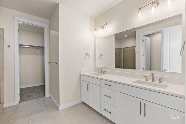 bathroom with a sink, a spacious closet, and a shower stall