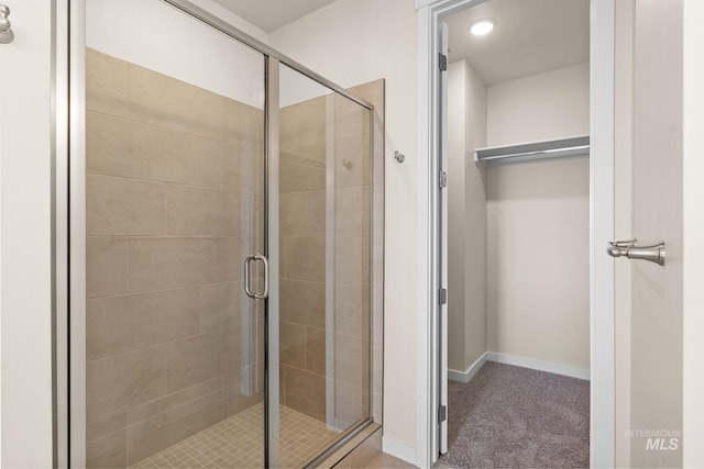 bathroom featuring a shower stall and baseboards