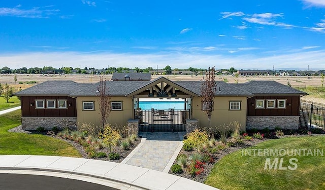 view of front of property featuring a gate, fence, a front lawn, stone siding, and board and batten siding