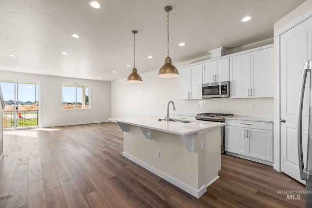 kitchen featuring decorative backsplash, appliances with stainless steel finishes, dark wood-style flooring, and a sink