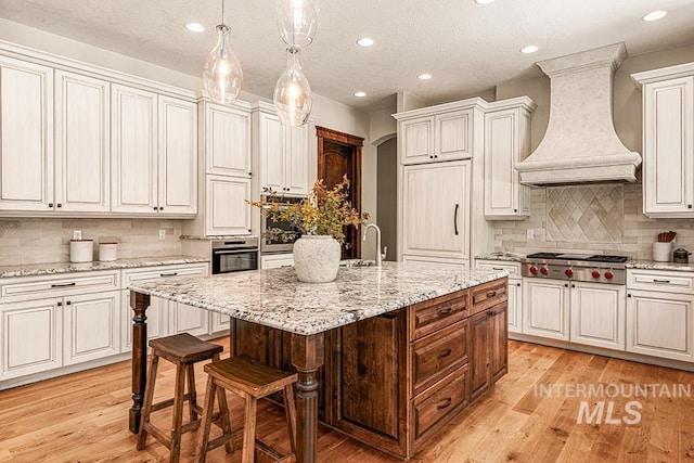 1452 S Hidden Island Pl, Eagle, ID 83616 - kitchen featuring appliances with stainless steel finishes, custom exhaust hood, backsplash, a kitchen island with sink, and recessed lighting