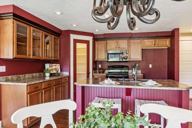 810 N Eagle Hills Way, Eagle, ID 83616 - kitchen featuring stainless steel appliances, glass insert cabinets, a kitchen island with sink, recessed lighting, and dark countertops