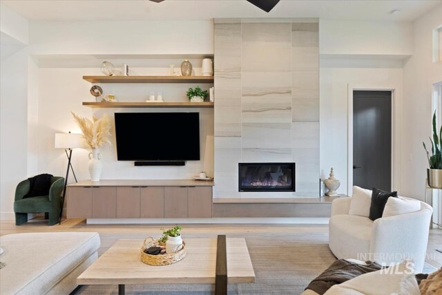 living room featuring a tiled fireplace and light wood-type flooring